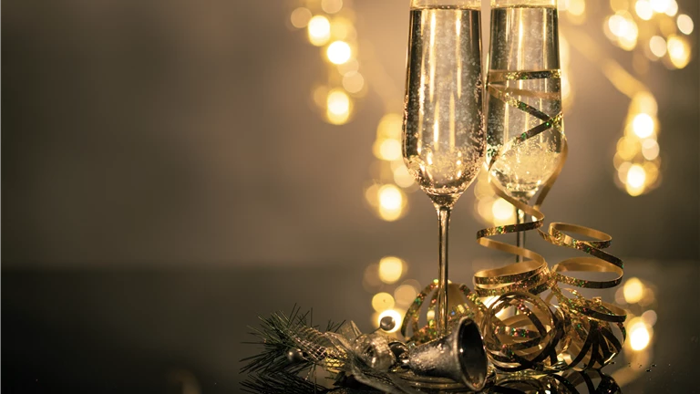 Close-Up Of Two Flute Glasses Filled With Sparkling Wine Wuth Ribbons And Christmas Decor