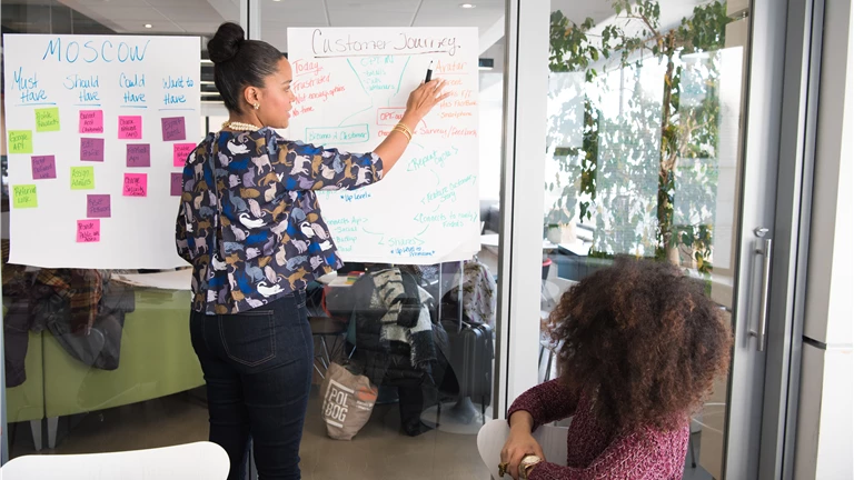Two Women Having a Meeting Inside Glass-panel Office